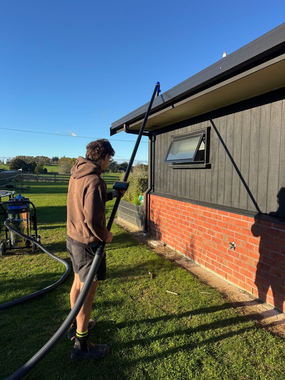 A Gutter Gators operator vacuuming a gutter from the ground with the SkyVac